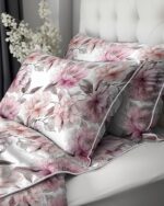 Floral pink and white pillowcase set on a white bed with soft gray piping details.