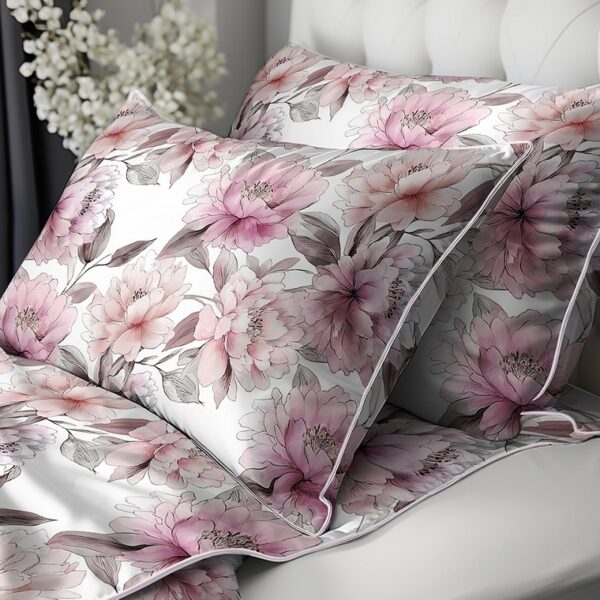 Floral pink and white pillowcase set on a white bed with soft gray piping details.