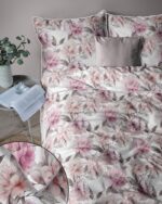 Bedroom scene featuring a floral pink peony-pattern duvet cover and matching pillowcases with a small gray throw pillow on the bed.