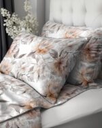 Floral-patterned bedding with peach and grey flowers on white, on a bed with a tufted headboard.
