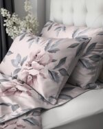 Soft pink floral bed linens with matching pillows on a white upholstered headboard, creating a cozy bedroom scene in pastel tones.