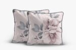 Two pink floral throw pillows with gray-edged borders leaning together on a light background.