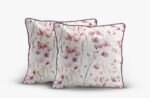 Three decorative throw pillows with a pale floral watercolor pattern and purple piping.