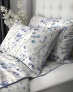 Twin beds with white floral-printed bedding and matching pillows featuring blue and lavender flowers on a white background.