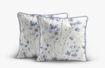 Three decorative throw pillows with a light cream background and blue-pink floral pattern, edged in blue piping.