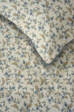 Beige wallpaper with blue and yellow floral pattern and a folded blue-edged corner showing the same design.