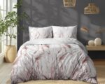 Queen bed with white duvet and pillows featuring pink grass pattern in a bright gray-walled bedroom with a tall plant by the window and woven pendant lights.
