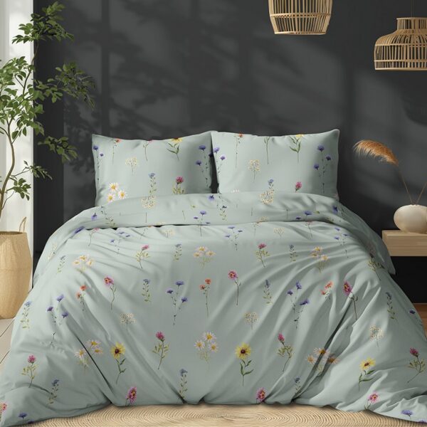 Bed with light blue floral duvet and matching pillows in a modern bedroom beside a tall plant.