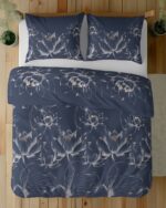 Overhead view of a bed with navy blue duvet cover and pillowcases featuring a white lotus flower pattern.