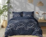 Bedroom with navy blue floral duvet and pillows, a potted plant by the window, and warm wicker lighting.