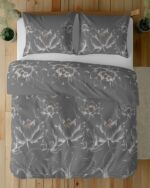 Top-down view of a bed with dark gray duvet and matching pillowcases adorned with white lotus flower designs.