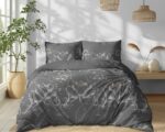 Gray bedspread with white floral pattern on a neatly made bed in a bright, sunlit bedroom.